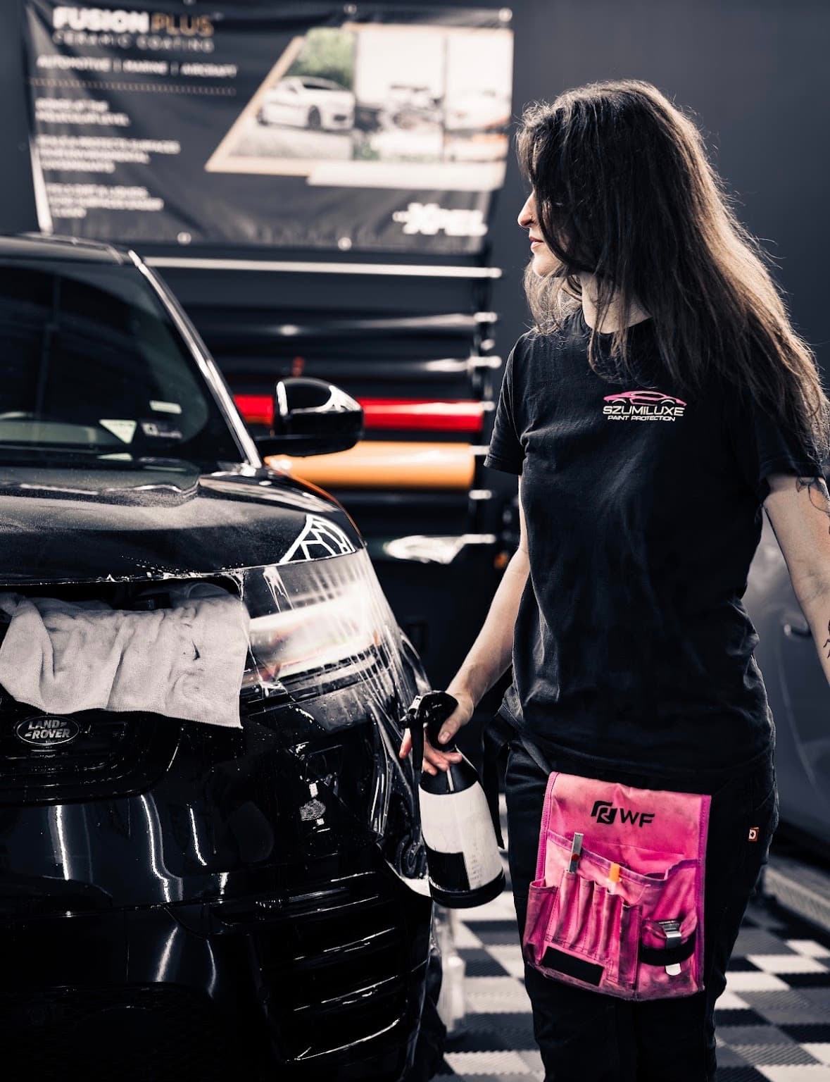 Szumiluxe technician hand-applying paint protection film to a vehicle